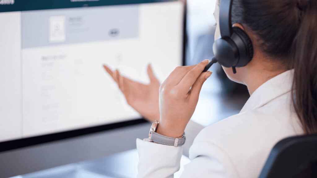 IT support technician with headset working on computer screen.