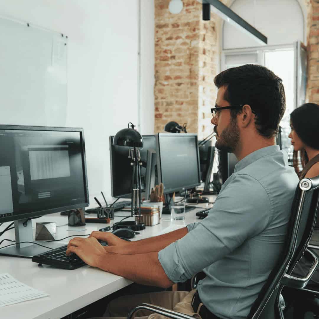 IT professional working at a computer in a modern office setting.